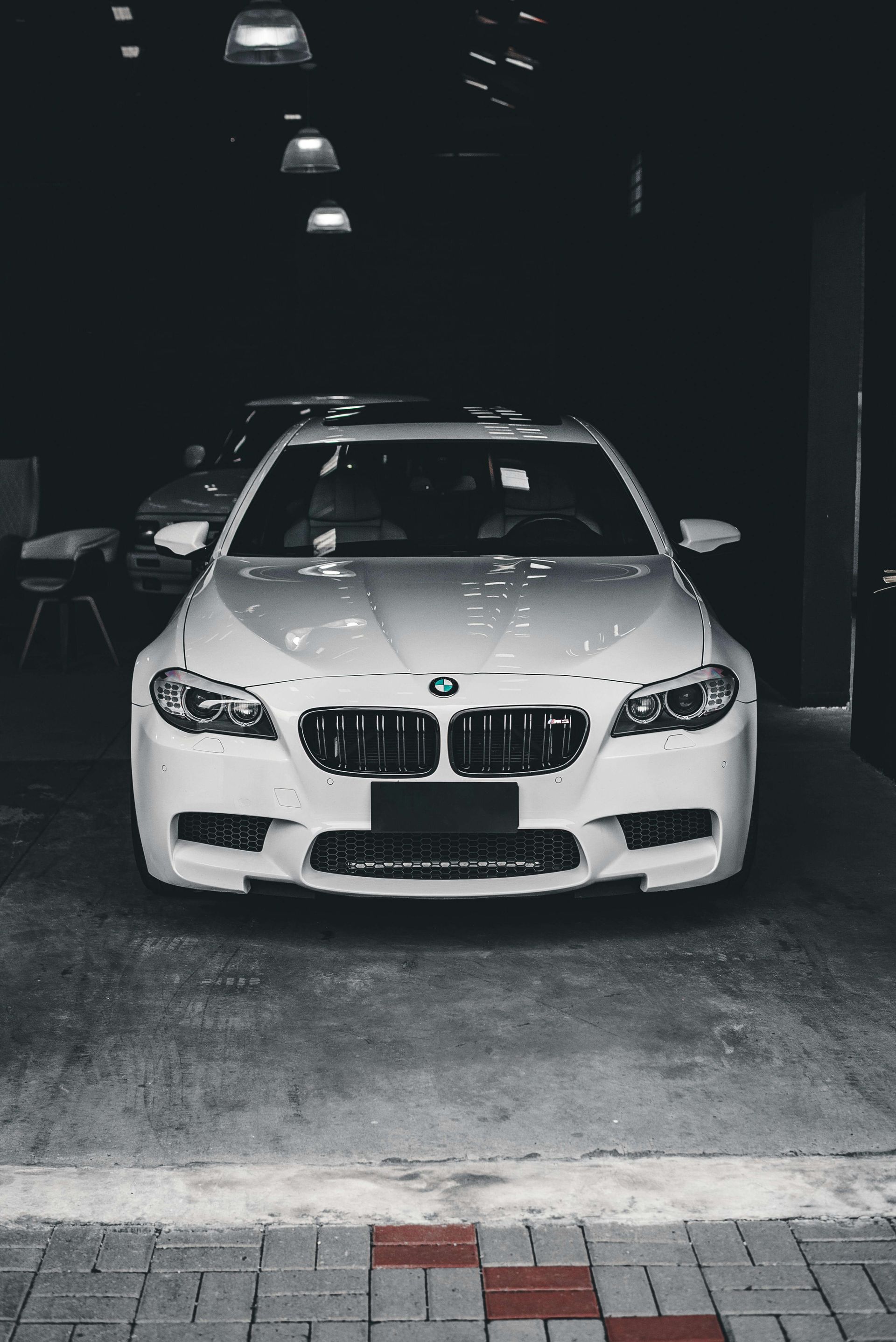 Black Audi R8 convertible parked on a street with other luxury cars. People in background.