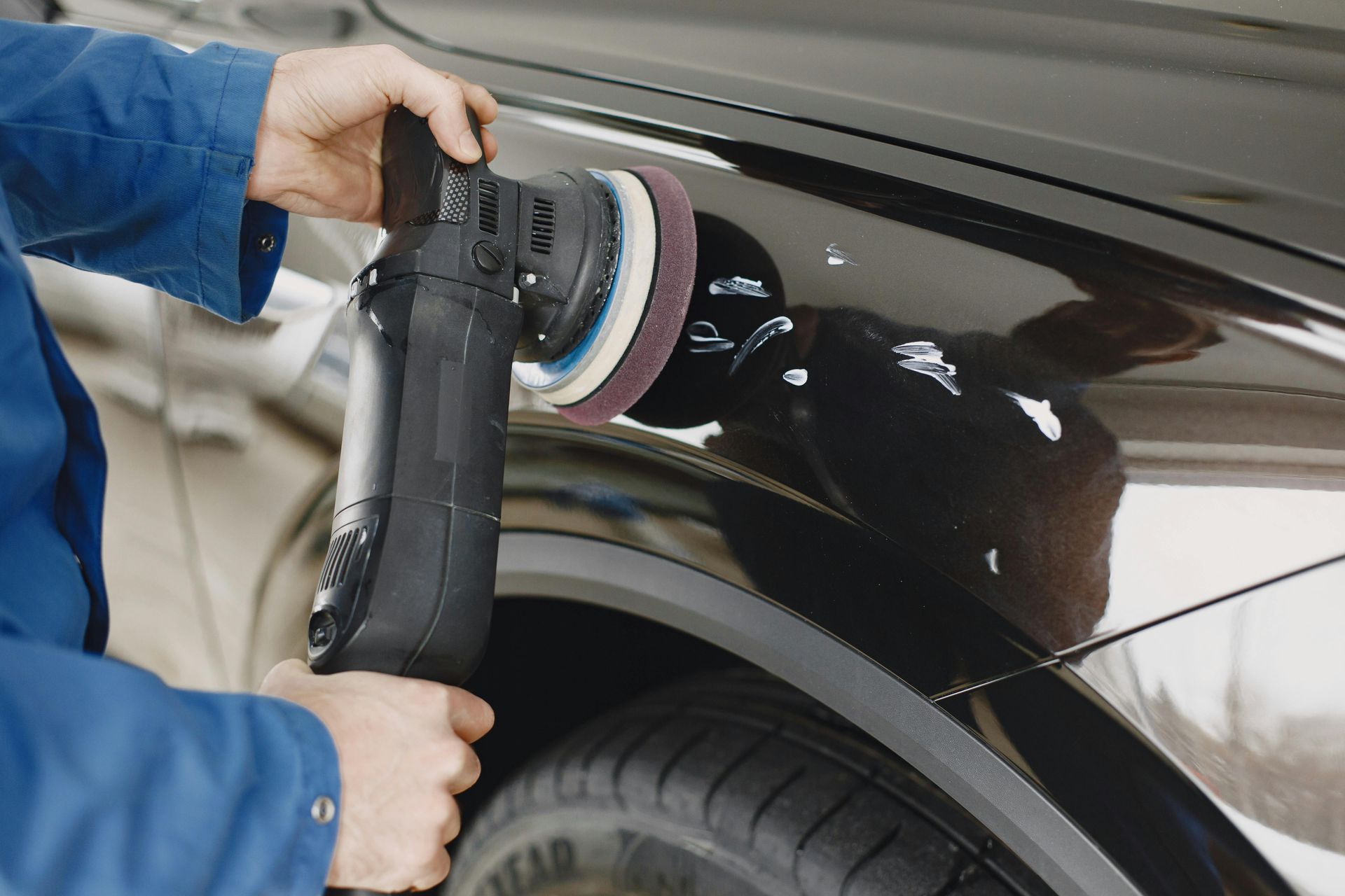 A man is polishing the fender of a black car