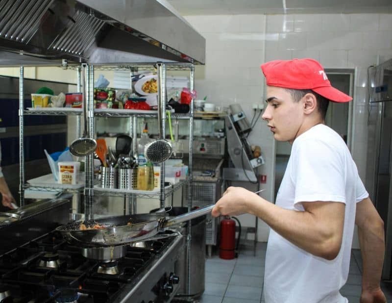A man in a red hat is cooking in a kitchen
