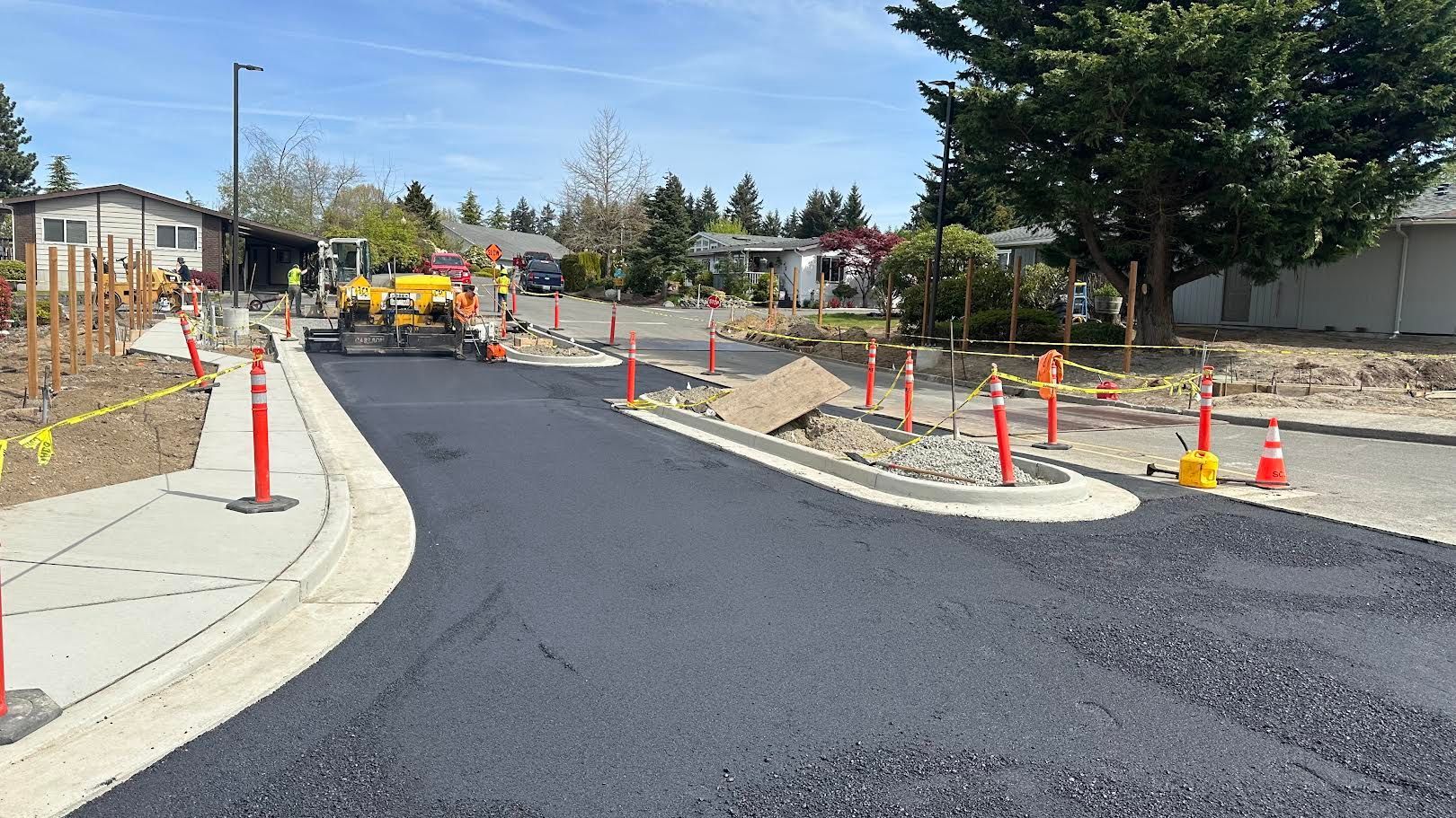 Road workers pouring asphalt from a truck onto a road surface.