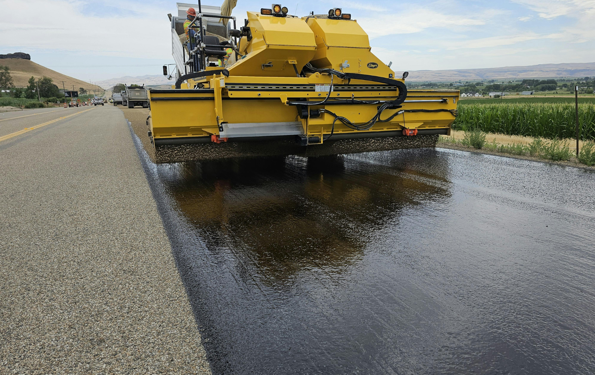Yellow road resurfacing machine spraying asphalt on a highway.