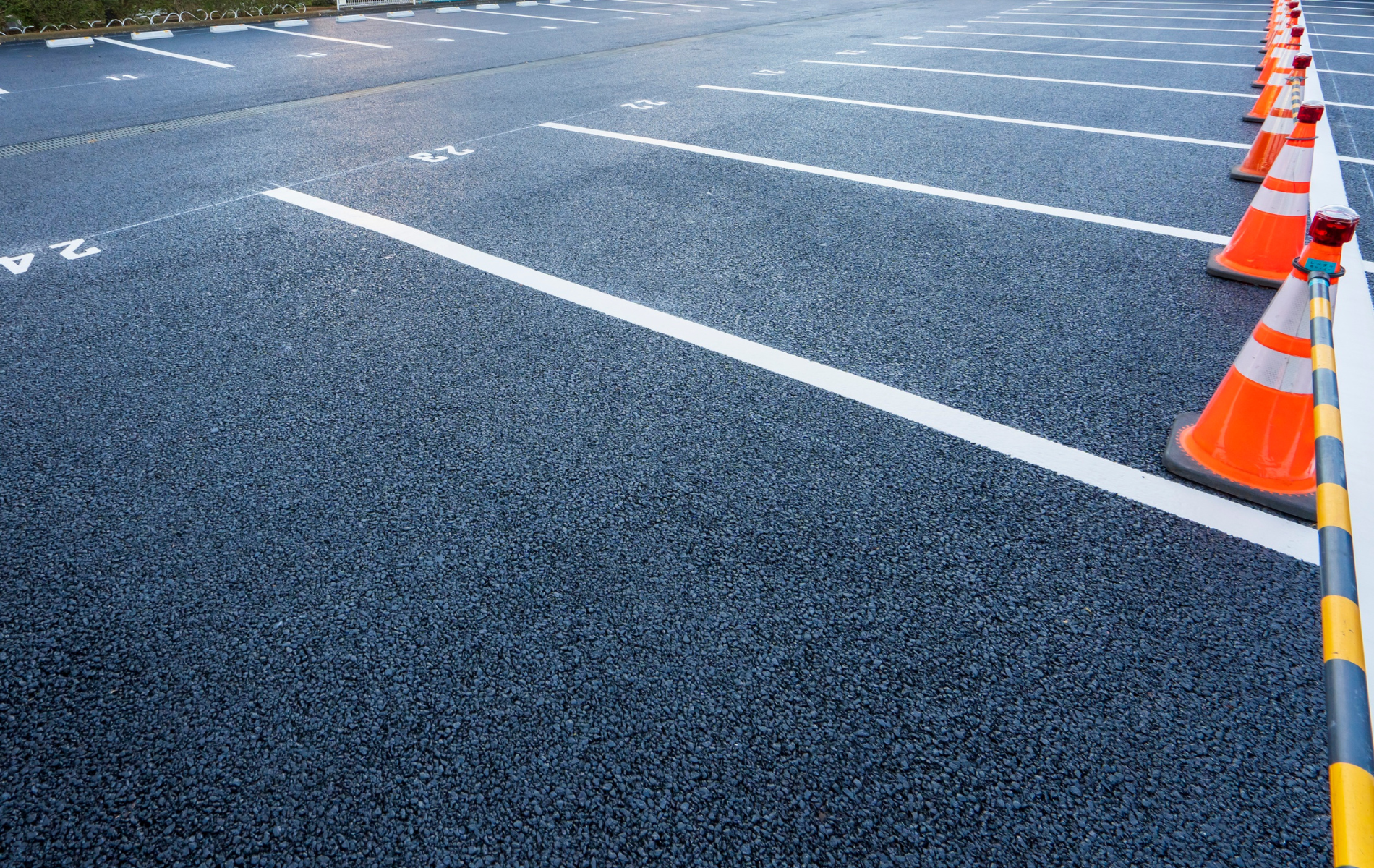 Parking lot with white lines, orange cones, and textured dark asphalt.