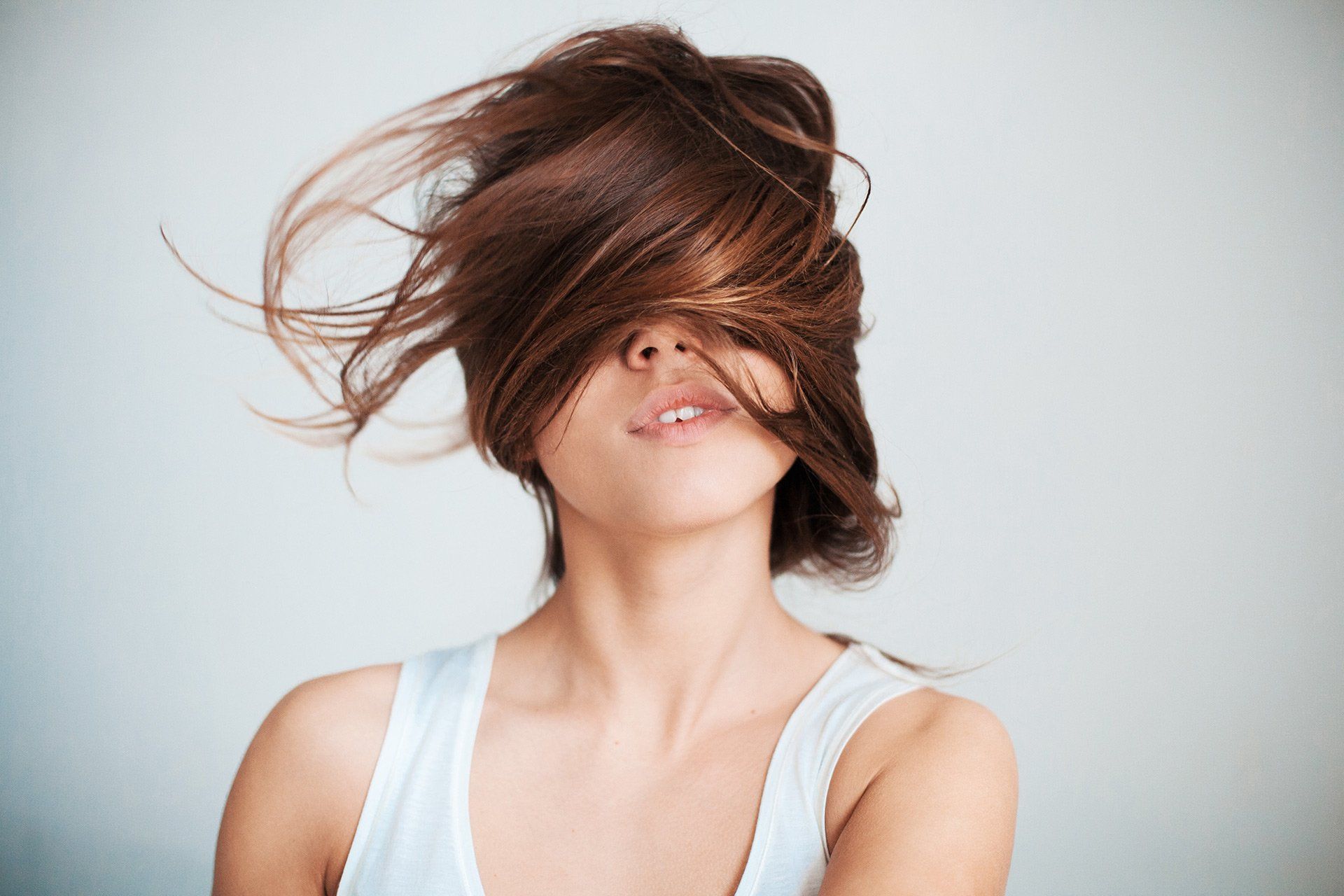 A woman with her hair blowing in the wind covering her face.