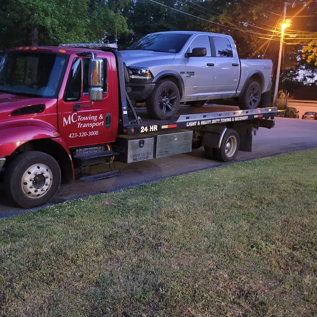 Black car being towed on a sunny day in front of a building with a