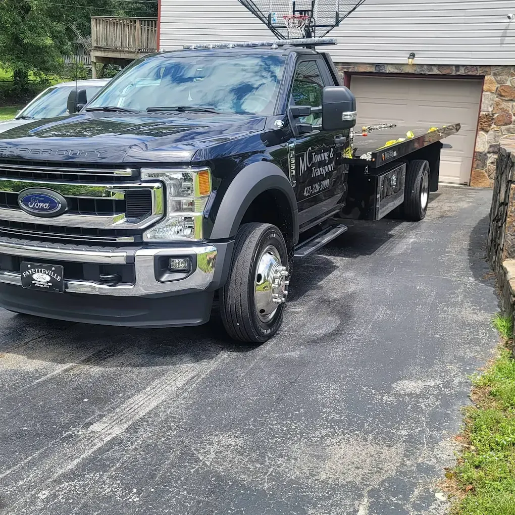 Black car being towed on a sunny day in front of a building with a