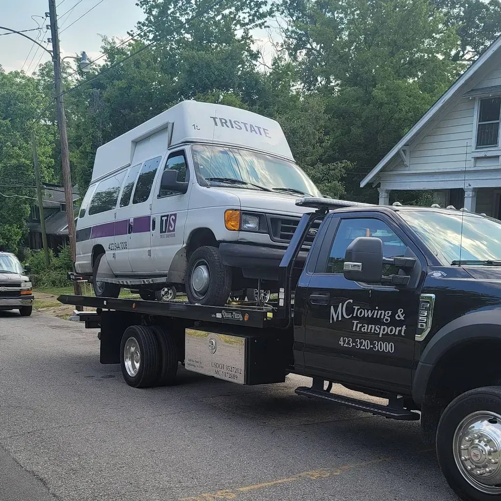 Red hot rod being towed on a flatbed tow truck. The truck is white.