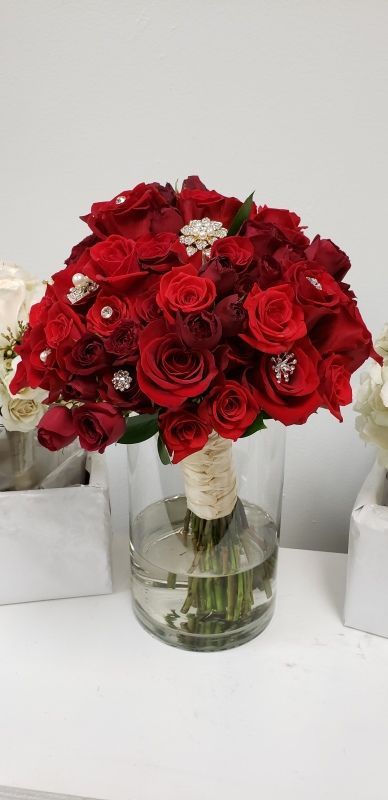 A vase filled with red roses is sitting on a table.