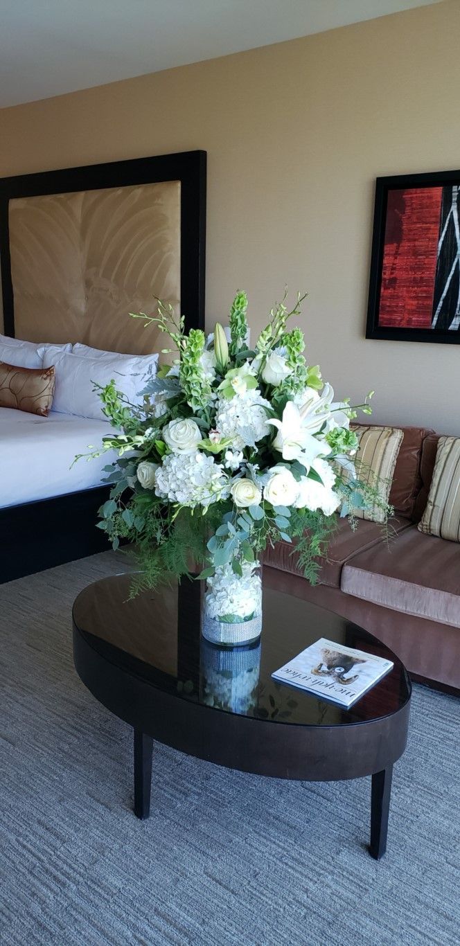 A vase of flowers is on a coffee table in a living room.
