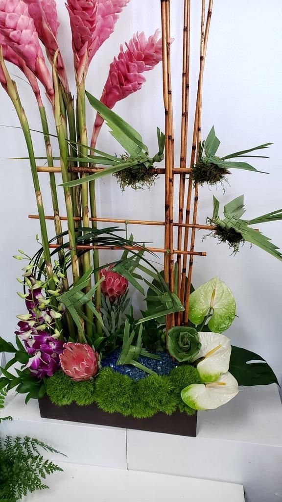 A vase filled with flowers and plants is sitting on a table.