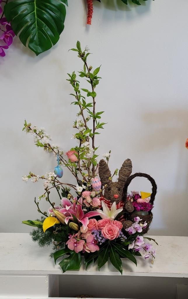 A basket filled with flowers and easter eggs on a table.