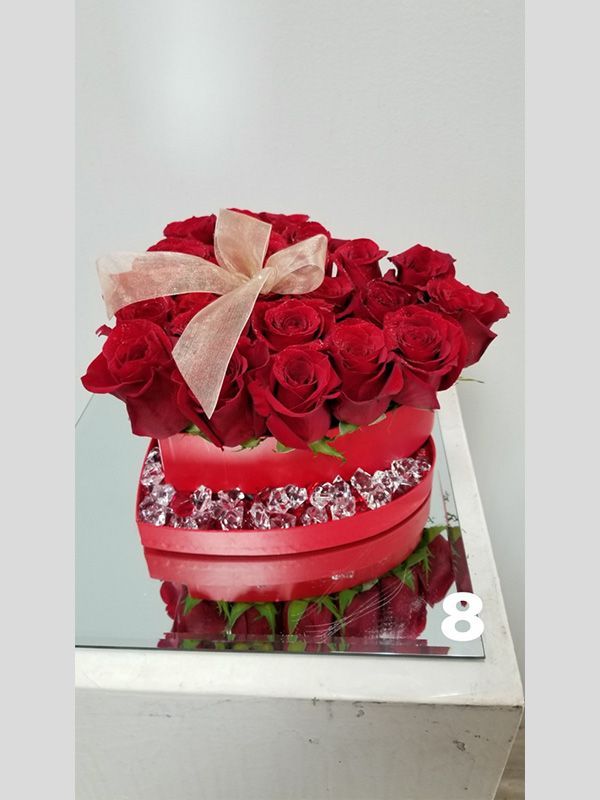 A heart shaped box filled with red roses and diamonds