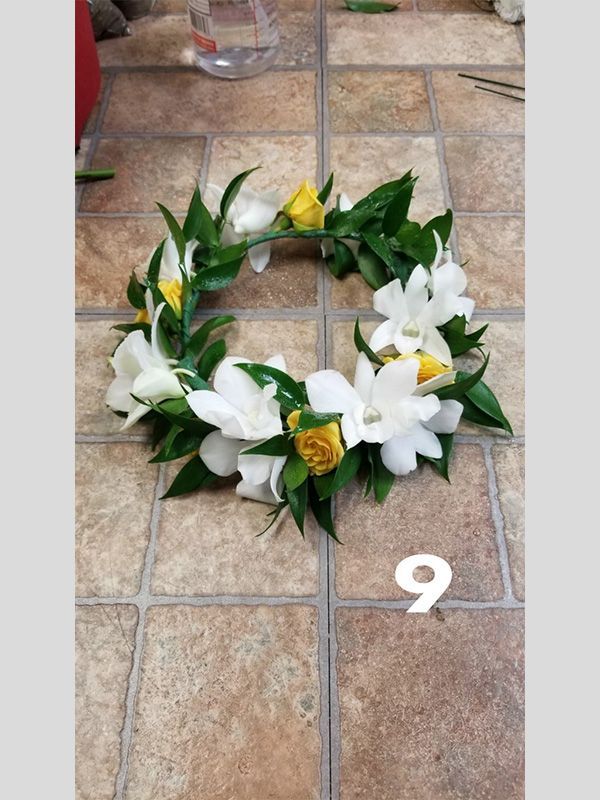 A wreath of white and yellow flowers with the number 9 on the bottom