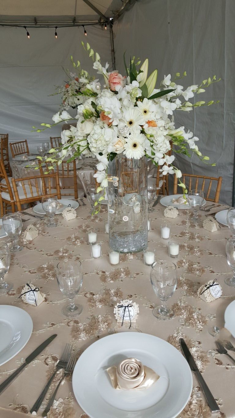A table with plates , utensils , and a vase of flowers on it.