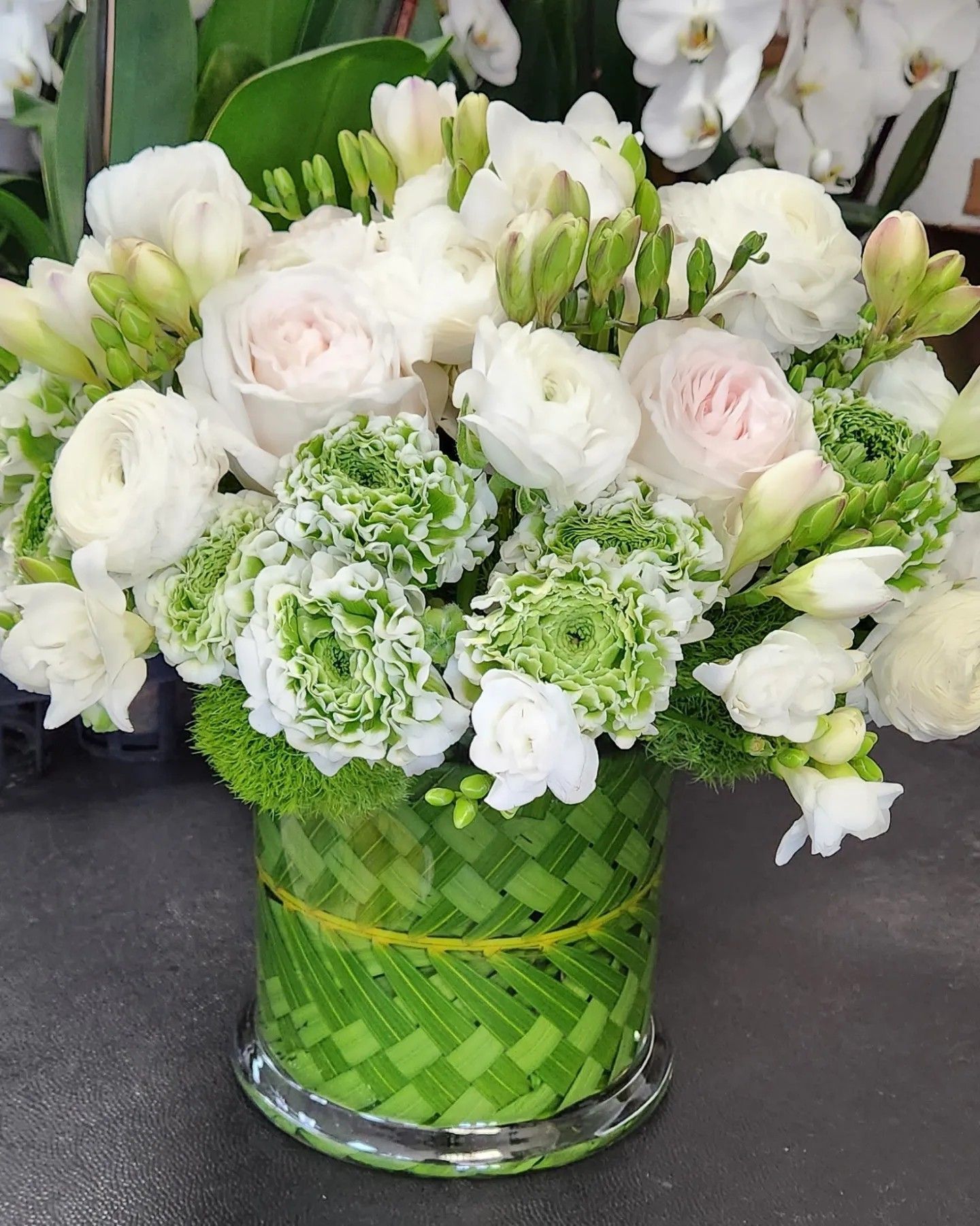 A vase filled with white and green flowers on a table