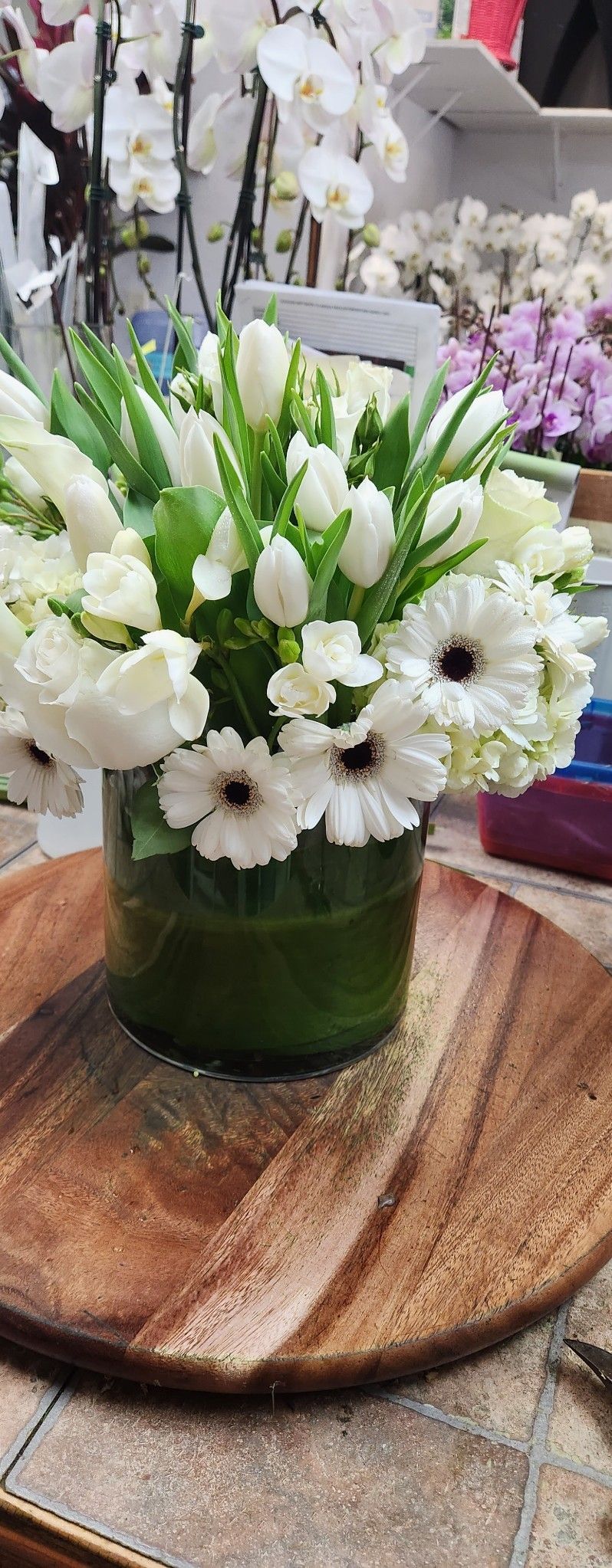 A vase filled with white flowers is sitting on a wooden table.