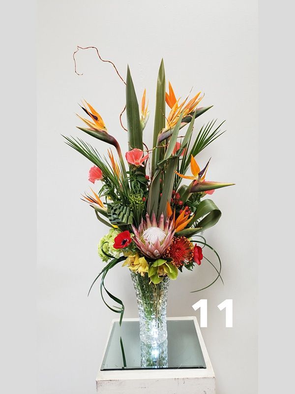 A vase filled with flowers is on a table with the number 11 on it.