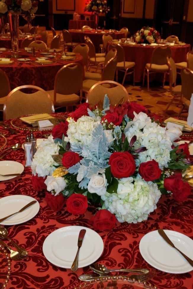 A table set for a banquet with red and white flowers on it