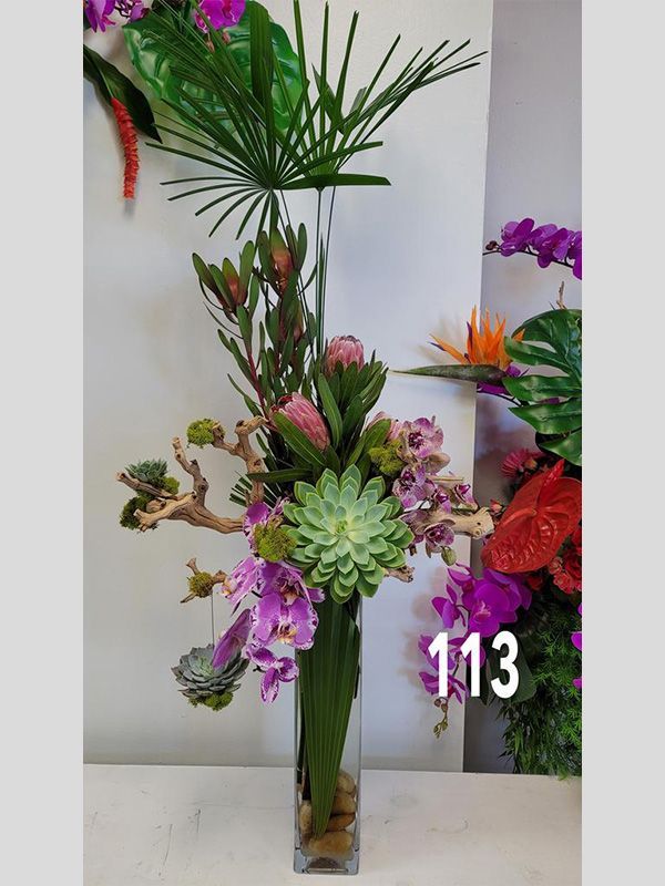 A vase filled with flowers and succulents with the number 113 on it