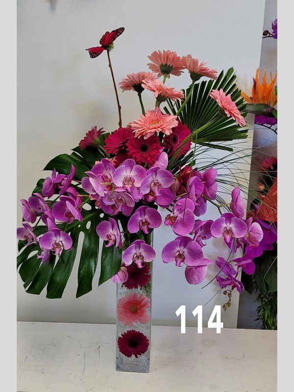 A vase filled with purple flowers and the number 114 on the bottom