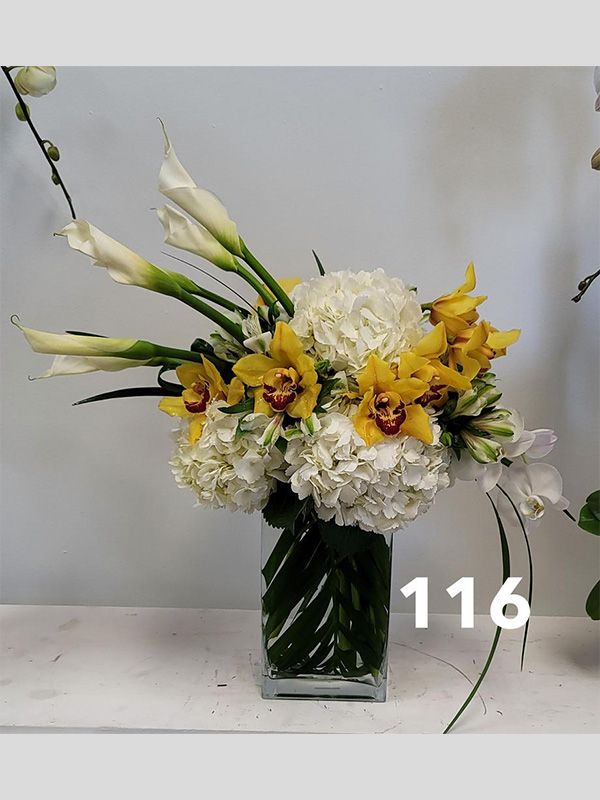 A vase filled with yellow and white flowers is sitting on a table.