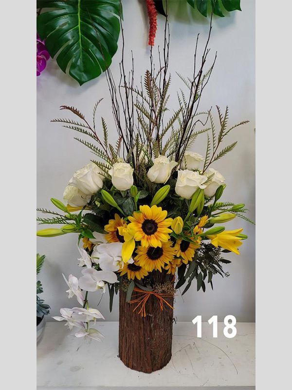 A wooden vase filled with sunflowers and white roses