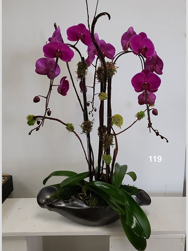 A vase filled with purple orchids is sitting on a table.