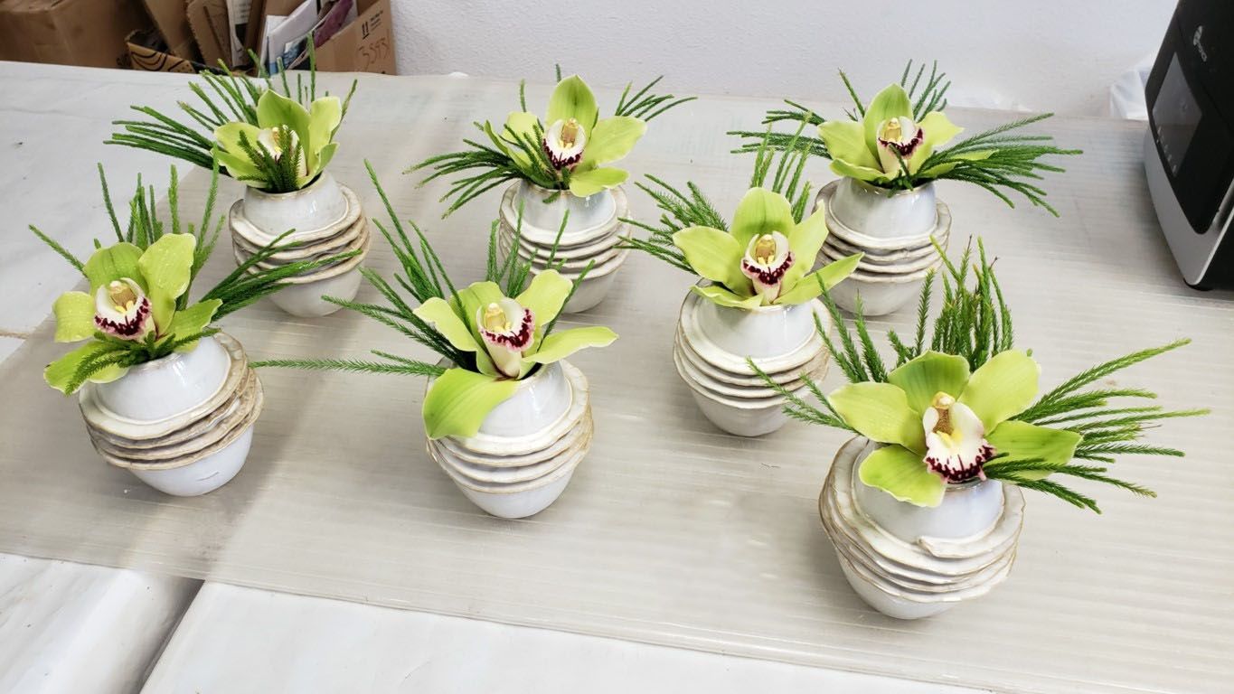 A bunch of vases filled with green flowers on a table