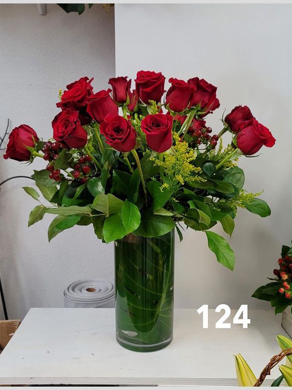 A vase filled with red roses and greenery has the number 124 on it