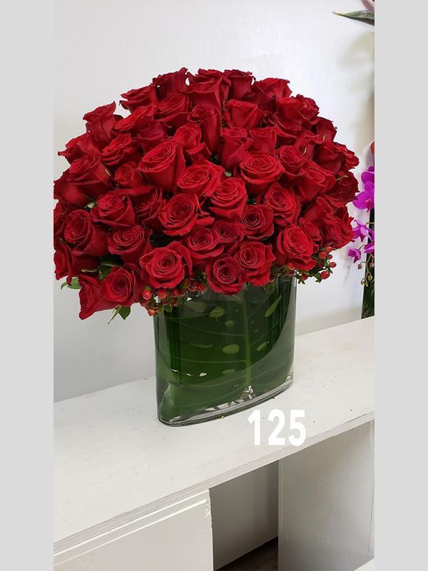 A vase filled with red roses has the number 125 on it