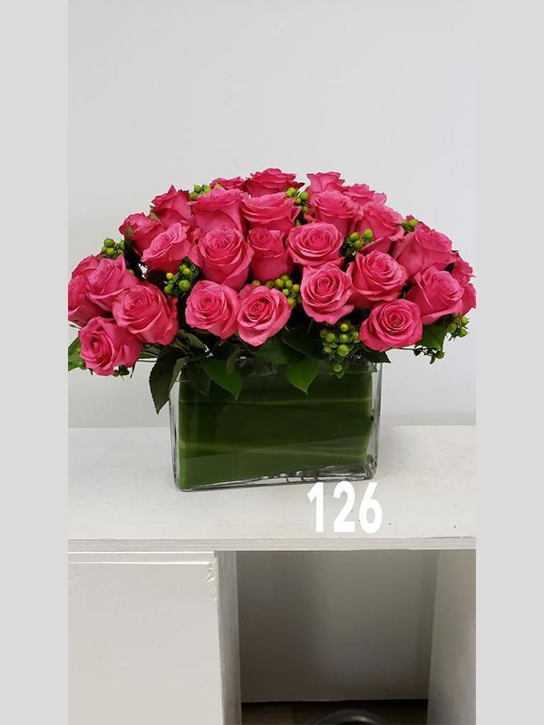 A vase filled with pink roses is sitting on a table.