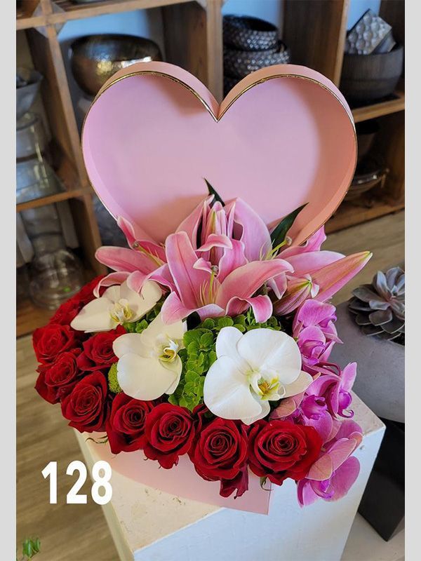 A heart shaped box filled with roses and lilies.