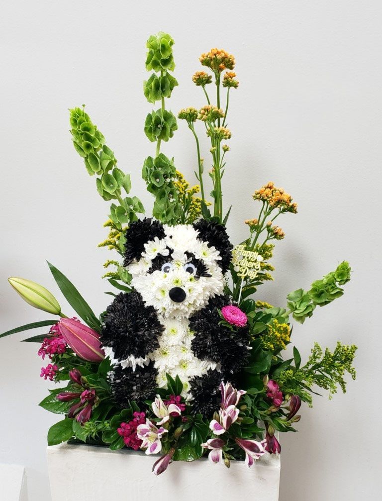 A panda made out of flowers is sitting on a table