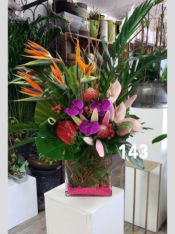 A vase filled with flowers and plants is sitting on a table.