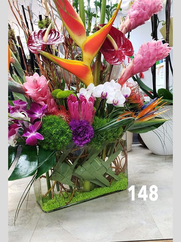 A vase filled with flowers and greenery is sitting on a table.
