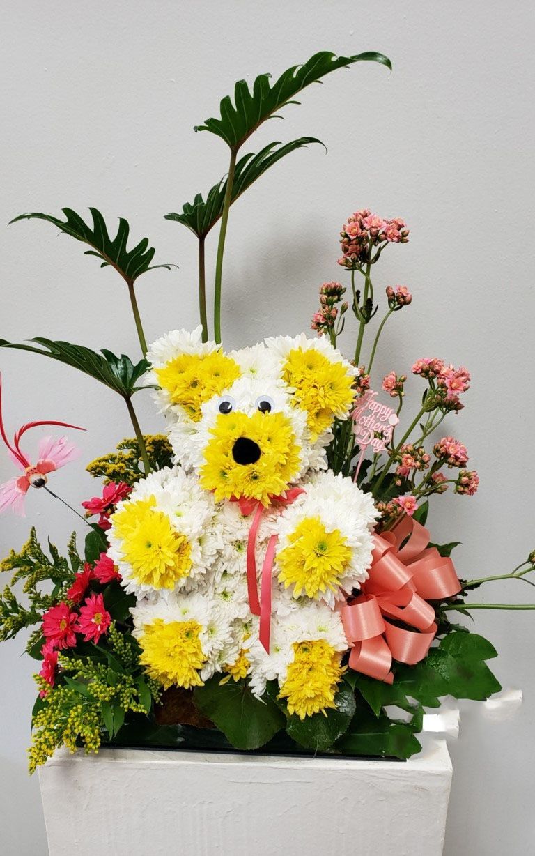 A teddy bear made out of yellow and white flowers