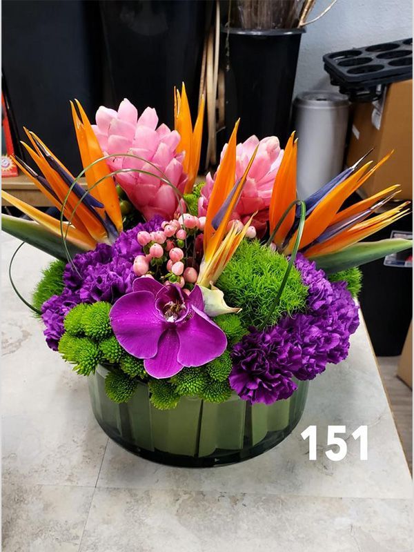 A vase filled with purple and orange flowers with the number 151 on the bottom