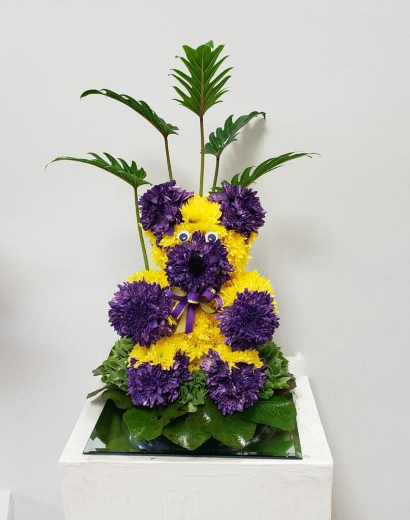 A teddy bear made of yellow and purple flowers