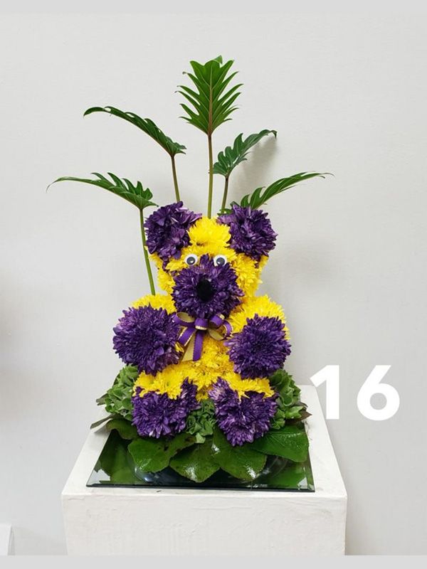 A teddy bear made out of purple and yellow flowers