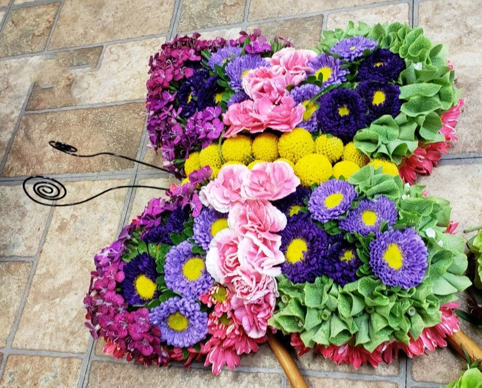 A butterfly made of flowers is sitting on a tiled floor