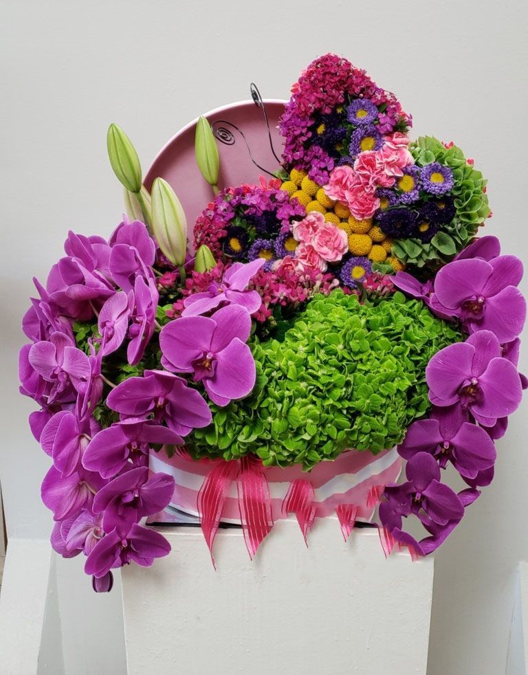 A heart shaped box filled with purple and green flowers