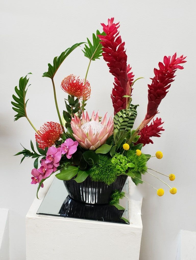 A vase filled with flowers is sitting on top of a mirror.