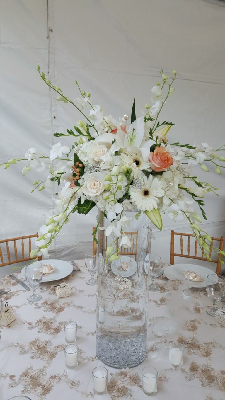 A table with a vase filled with white flowers and candles on it.