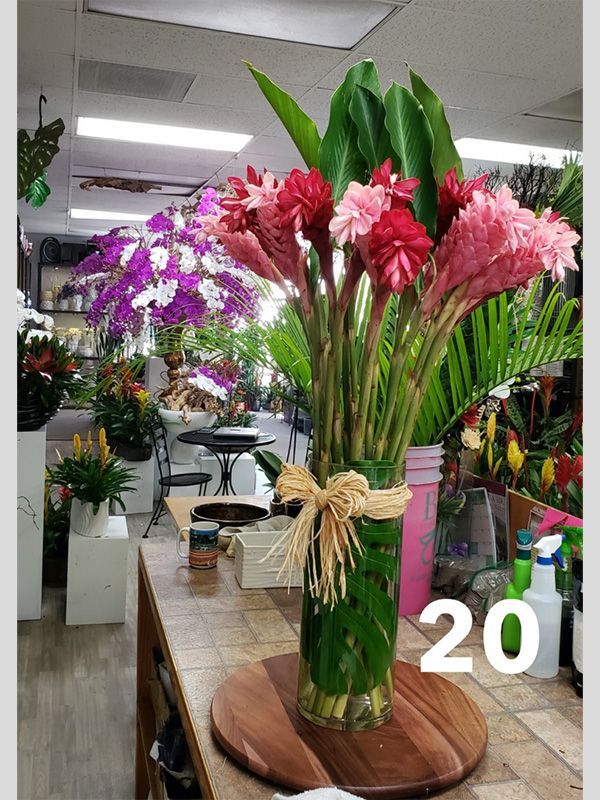 A vase filled with pink and red flowers is sitting on a wooden table.