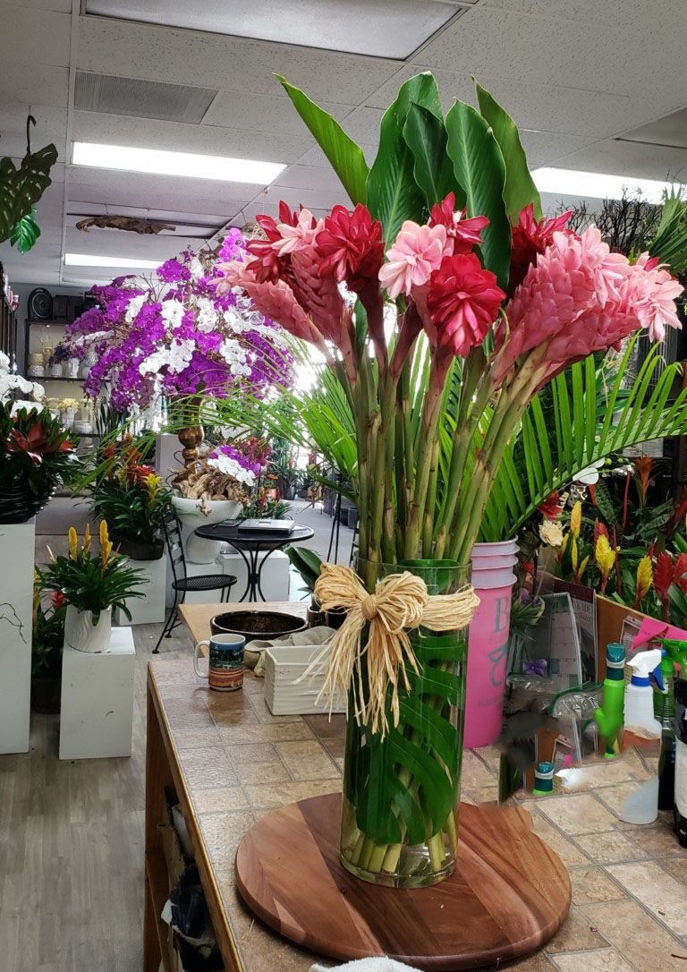 A vase filled with pink and red flowers is sitting on a wooden table.