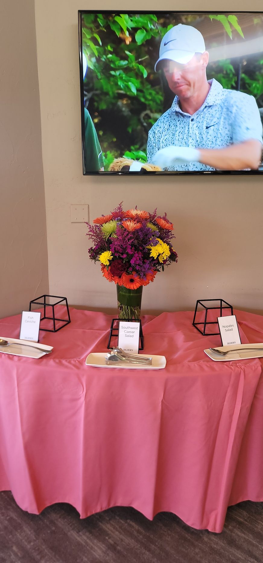 A table with a pink tablecloth and a vase of flowers on it.