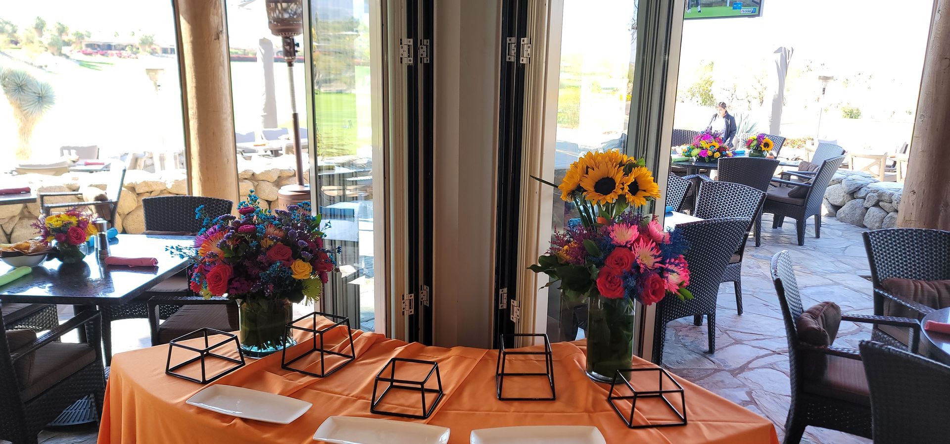 A table with plates and vases of flowers on it in a restaurant.