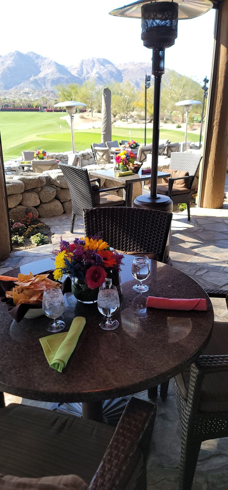A table with a vase of flowers on it and a patio heater.