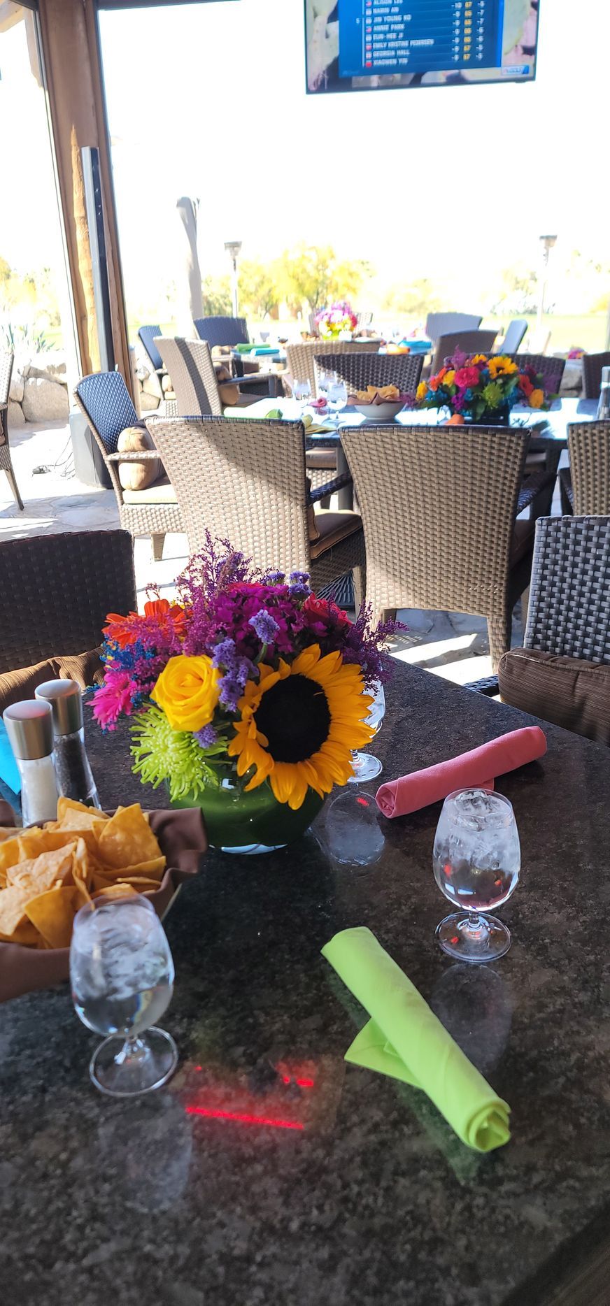A table with a vase of flowers and glasses on it.