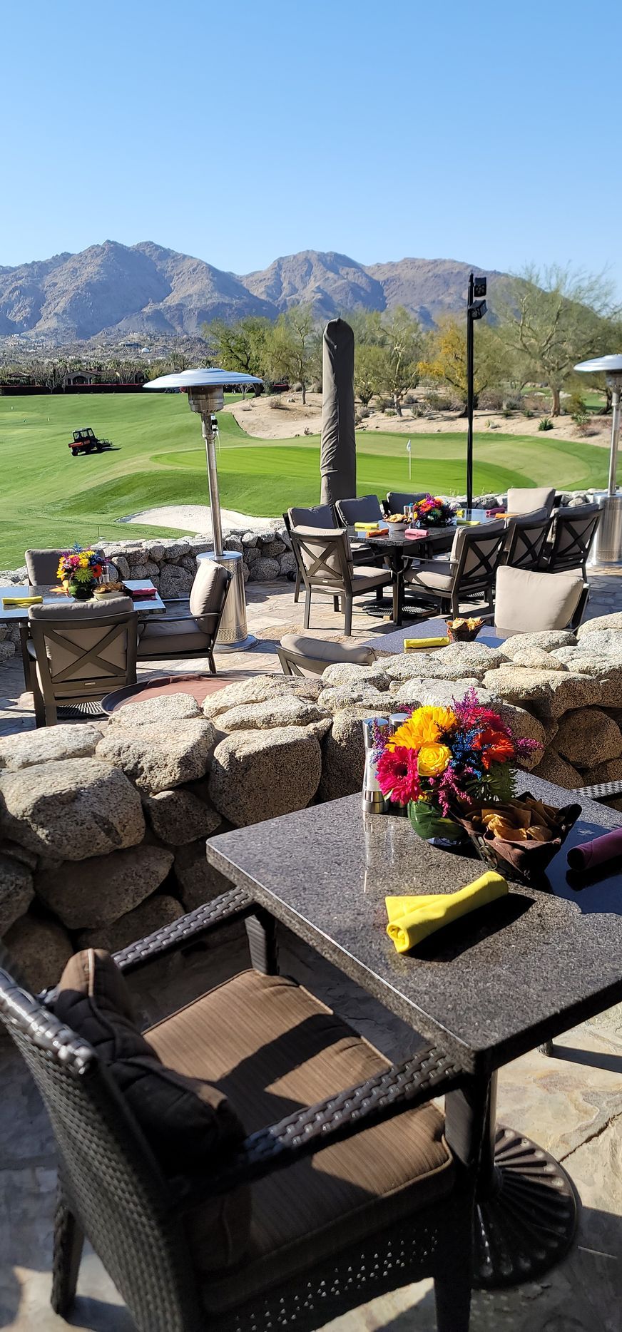 A table and chairs on a patio with mountains in the background.