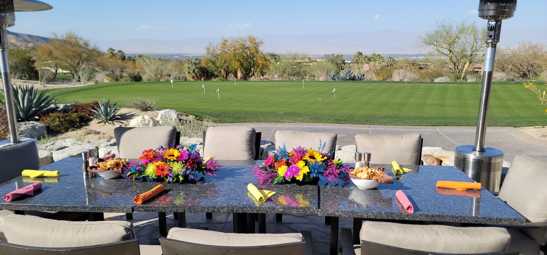 A dining table with flowers on it and a view of a golf course.
